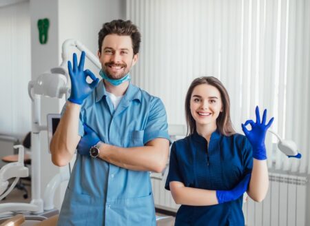 photo-smiling-dentist-standing-with-arms-crossed-with-her-colleague-showing-okay-sign_496169-1043